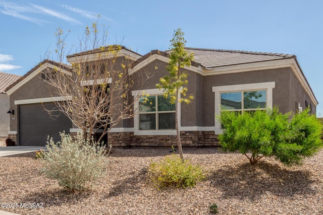 view of front of house with a tiled roof, a garage, stone siding, and stucco siding