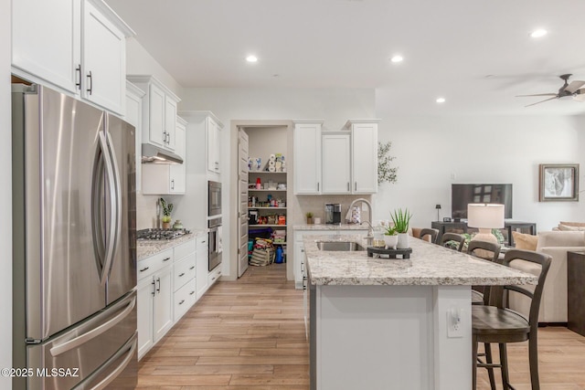 kitchen with a sink, appliances with stainless steel finishes, open floor plan, and white cabinetry