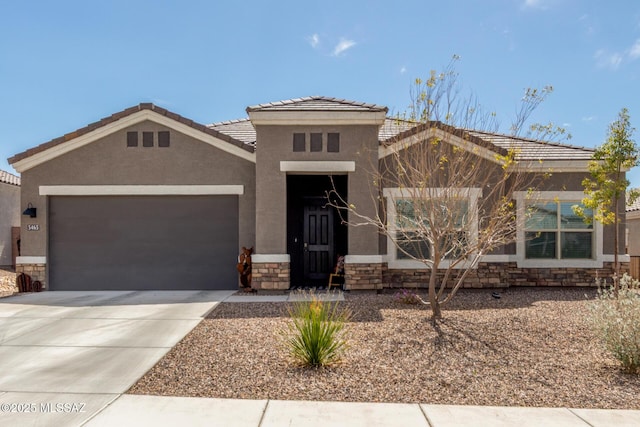 view of front of house featuring stucco siding, a tile roof, stone siding, concrete driveway, and a garage