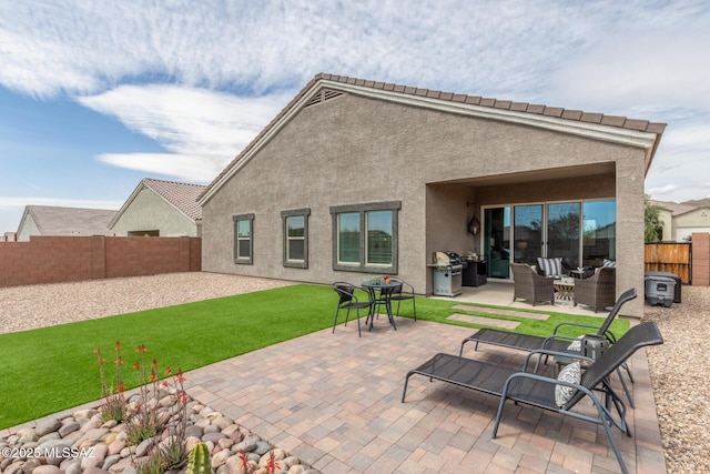 rear view of house featuring stucco siding, a patio, a lawn, and a fenced backyard