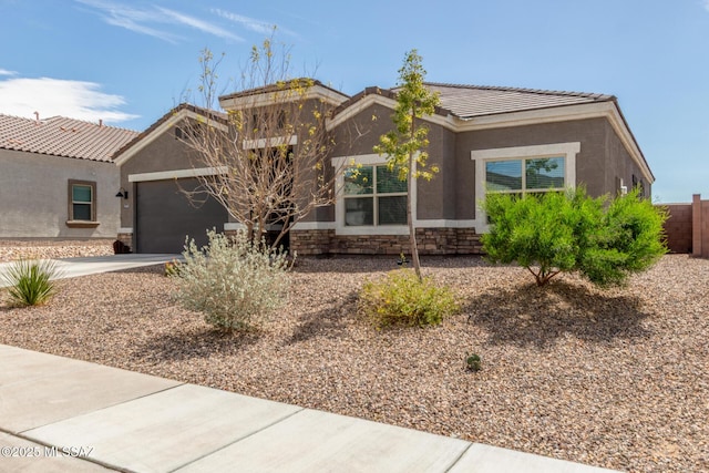 view of front of property featuring a tiled roof, stone siding, driveway, and stucco siding