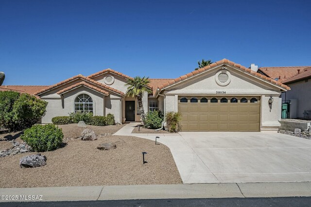 38034 S Golf Course Dr, Saddlebrooke, AZ 85739 - mediterranean / spanish-style home with concrete driveway, an attached garage, a tile roof, and stucco siding