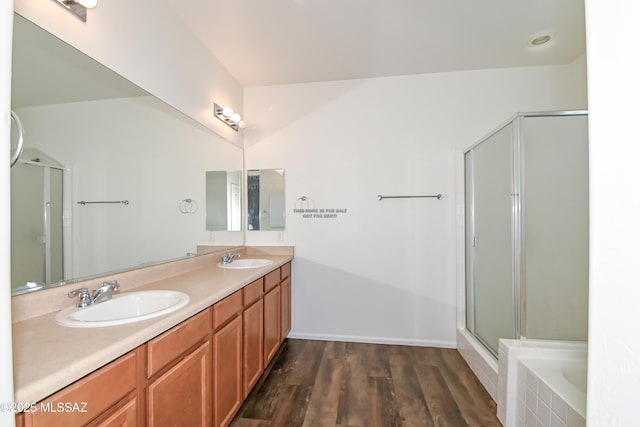 full bath with double vanity, a stall shower, wood finished floors, and a sink