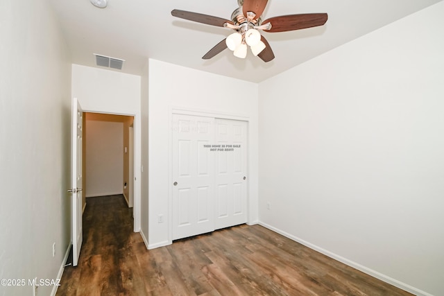 unfurnished bedroom featuring wood finished floors, visible vents, a closet, and baseboards