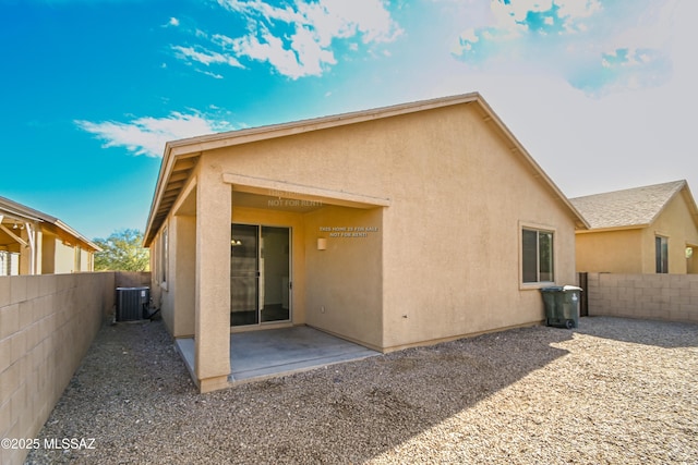 rear view of house featuring stucco siding, a patio, central AC unit, and a fenced backyard