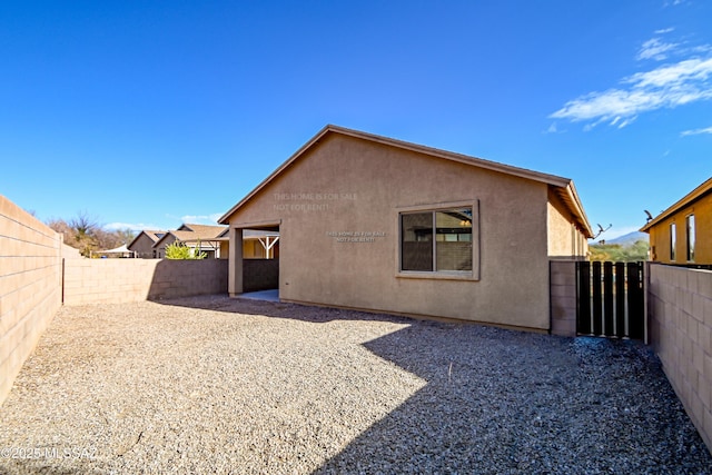 rear view of property featuring stucco siding, a patio, and a fenced backyard