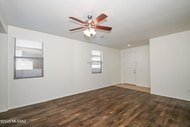 unfurnished room with a ceiling fan, wood finished floors, visible vents, and baseboards