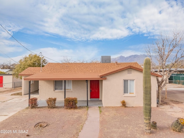 view of front facade with an attached carport, fence, a porch, stucco siding, and concrete driveway