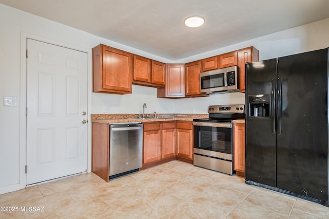 kitchen featuring a sink, stainless steel appliances, brown cabinetry, and light tile patterned floors