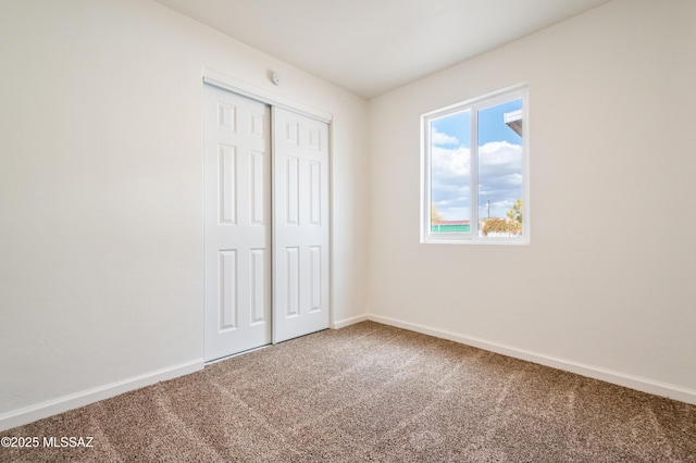 unfurnished bedroom featuring a closet, baseboards, and carpet floors