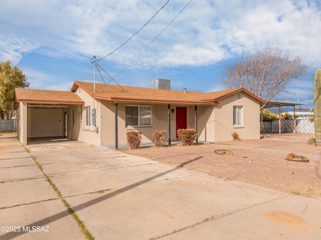 ranch-style house with stucco siding, driveway, and fence