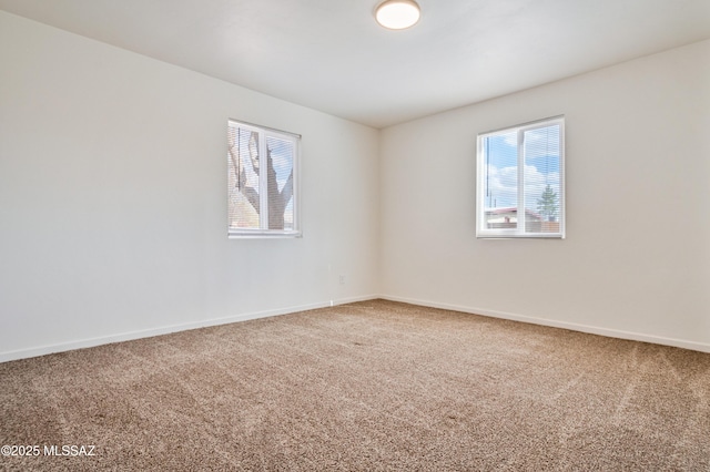 carpeted empty room featuring baseboards