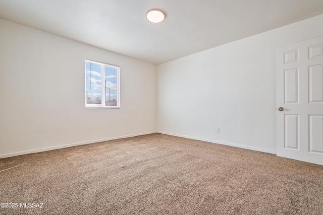 carpeted spare room featuring baseboards