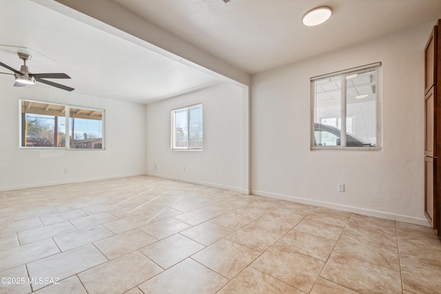 spare room with light tile patterned flooring, a ceiling fan, and baseboards