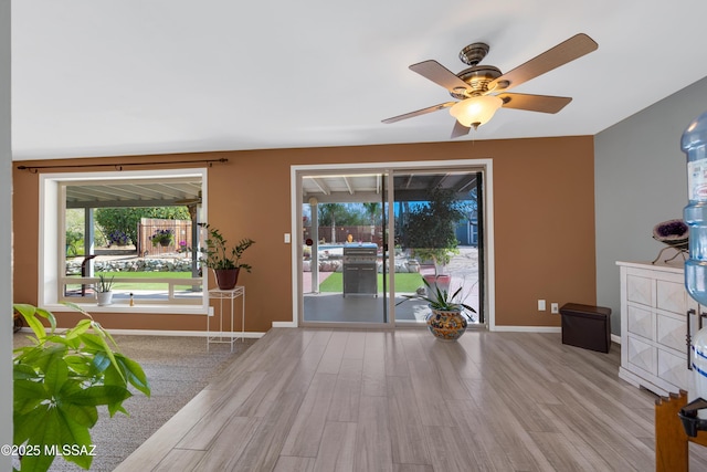 interior space with plenty of natural light, wood finished floors, baseboards, and ceiling fan