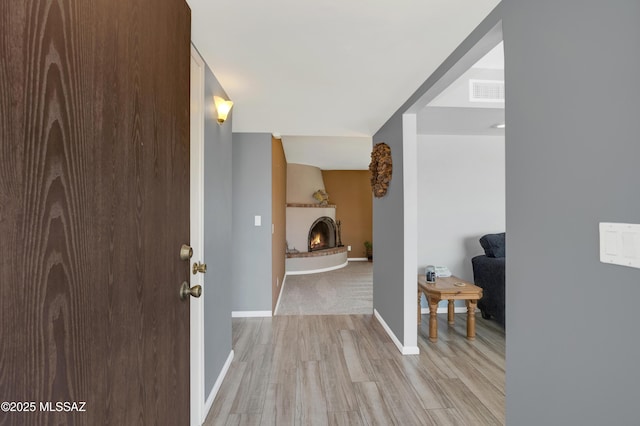 corridor with light wood-style flooring, baseboards, and visible vents