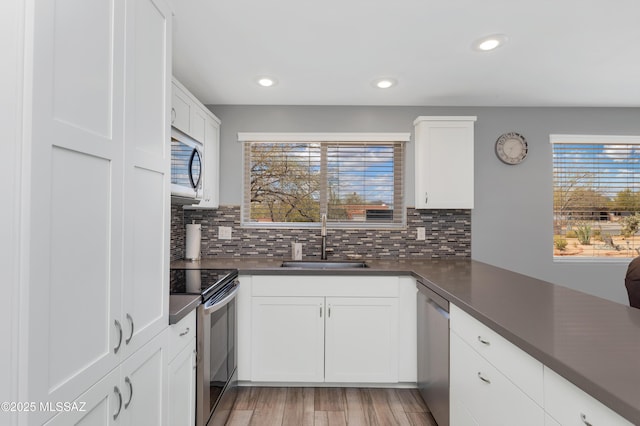 kitchen with a sink, stainless steel appliances, dark countertops, and a healthy amount of sunlight