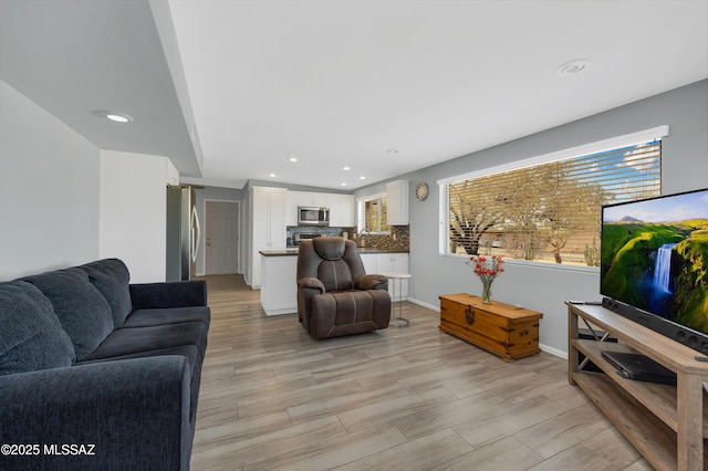 living room featuring recessed lighting, light wood-style flooring, and baseboards