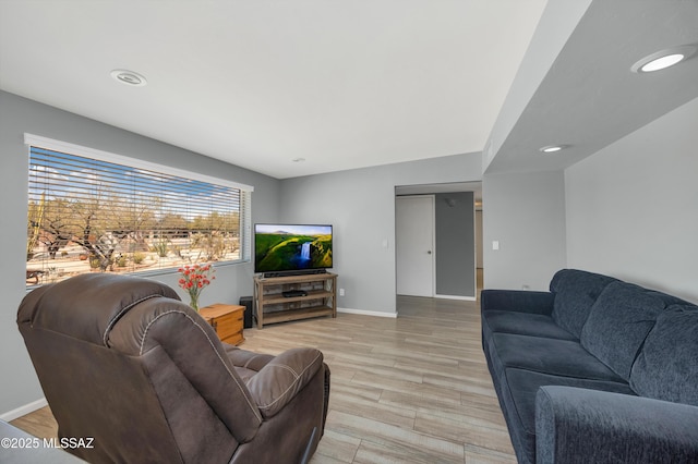 living room featuring recessed lighting, baseboards, and light wood-type flooring