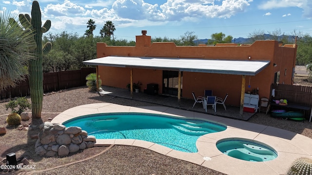 view of swimming pool with a patio, a fenced in pool, a fenced backyard, and an in ground hot tub