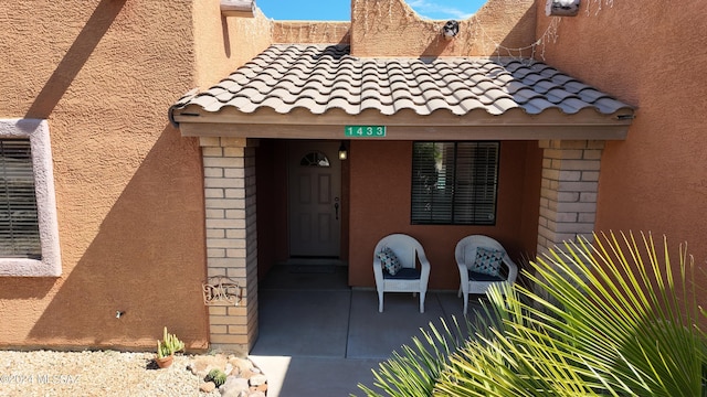 view of exterior entry with a tiled roof and stucco siding