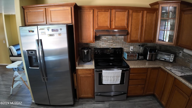 kitchen featuring black electric range, stainless steel fridge with ice dispenser, brown cabinets, and under cabinet range hood