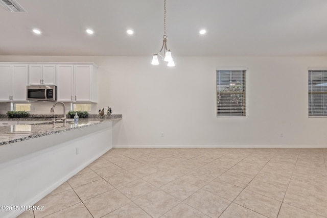 kitchen featuring light stone counters, visible vents, pendant lighting, white cabinetry, and stainless steel microwave