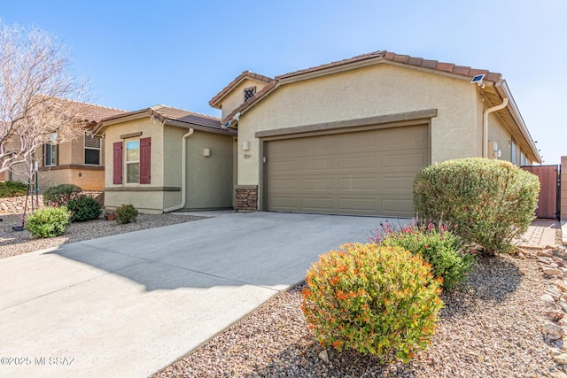 view of front of property with a tiled roof, a garage, driveway, and stucco siding