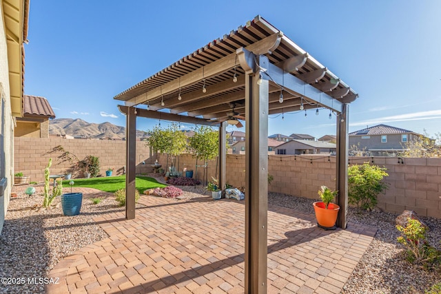 view of patio featuring ceiling fan, a mountain view, and a fenced backyard