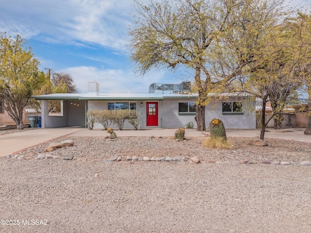 ranch-style home featuring an attached carport, concrete driveway, and a chimney