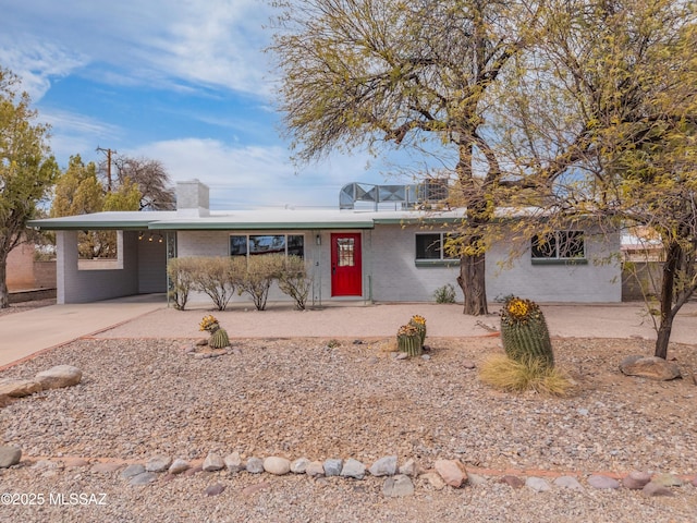 ranch-style home featuring an attached carport, brick siding, driveway, and a chimney