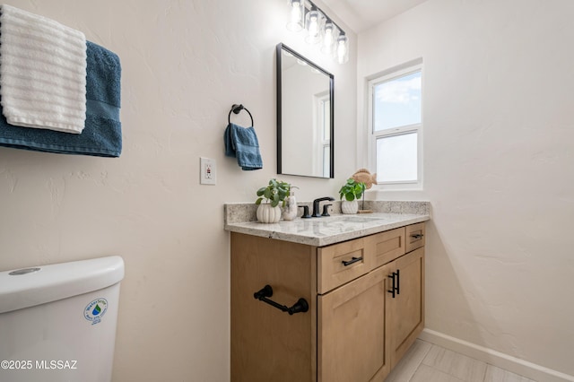 bathroom with toilet, vanity, and baseboards