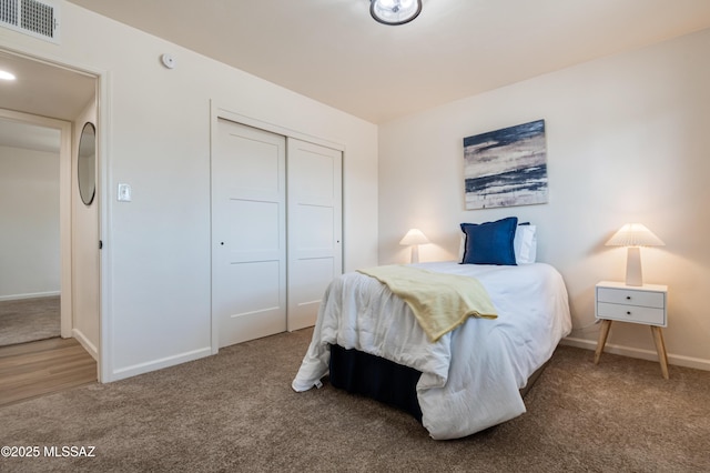 carpeted bedroom with a closet, visible vents, and baseboards