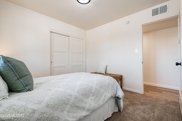 carpeted bedroom with a closet, visible vents, and baseboards