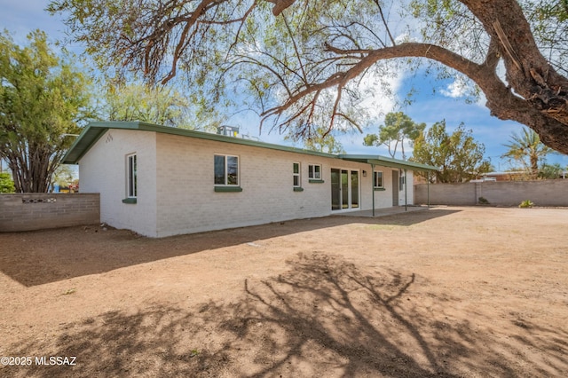 rear view of property with brick siding, a patio area, and a fenced backyard