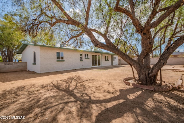 rear view of house with a patio, brick siding, and fence