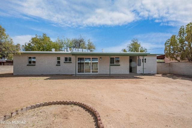 back of house featuring fence and brick siding