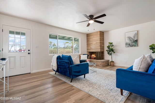 living room with a fireplace, baseboards, ceiling fan, and wood finished floors