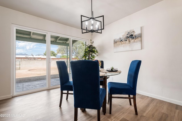 dining area with a chandelier, baseboards, and wood finished floors