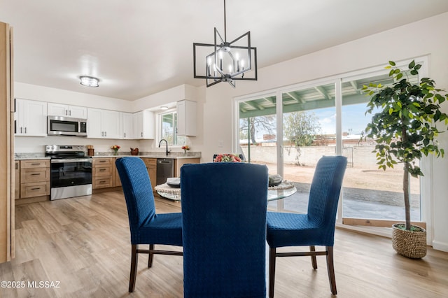 dining space with a notable chandelier, a healthy amount of sunlight, and light wood-style flooring