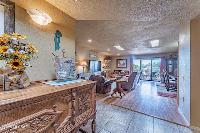 tiled living room with a textured ceiling, baseboards, and a textured wall