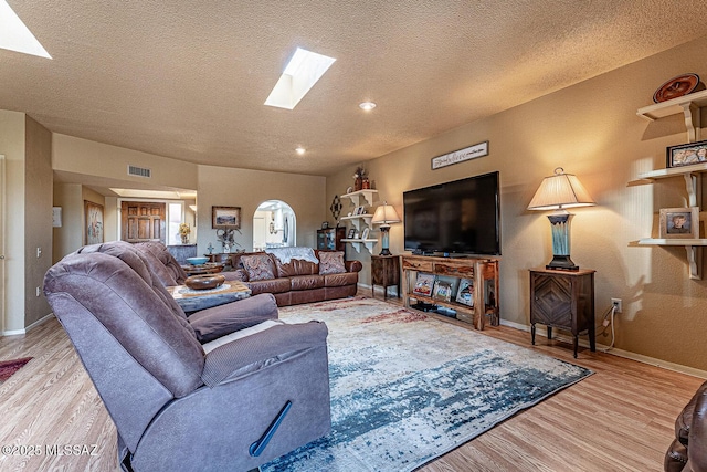 living area featuring visible vents, a skylight, baseboards, and wood finished floors