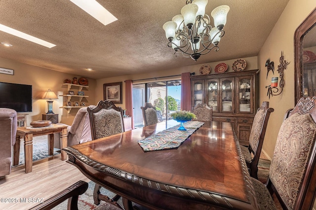 dining room featuring light wood-type flooring, a textured ceiling, and a chandelier