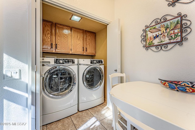 clothes washing area featuring light tile patterned floors, cabinet space, and washer and clothes dryer