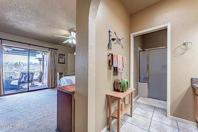 corridor with light tile patterned floors, baseboards, a textured ceiling, and a textured wall