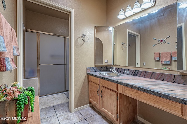 full bathroom with tile patterned flooring, a shower stall, vanity, and a textured wall