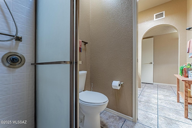 bathroom with visible vents, baseboards, tile patterned floors, toilet, and a textured wall