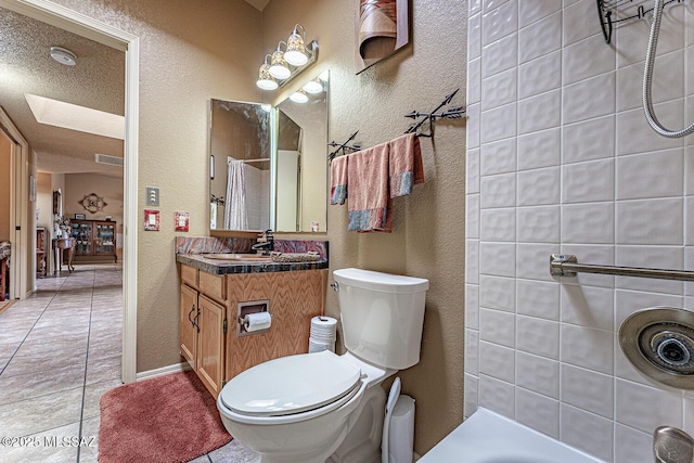 full bath with tile patterned flooring, toilet, and a textured wall