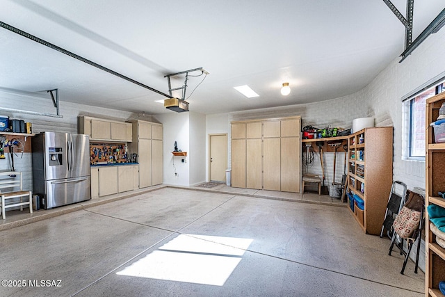 garage with a garage door opener and stainless steel refrigerator with ice dispenser