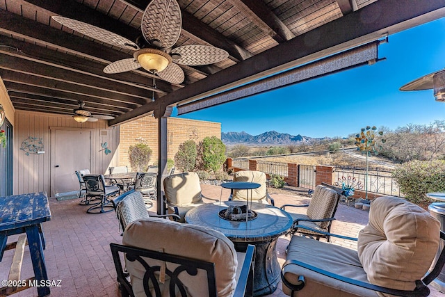 view of patio / terrace with outdoor dining space, fence, a mountain view, and a ceiling fan